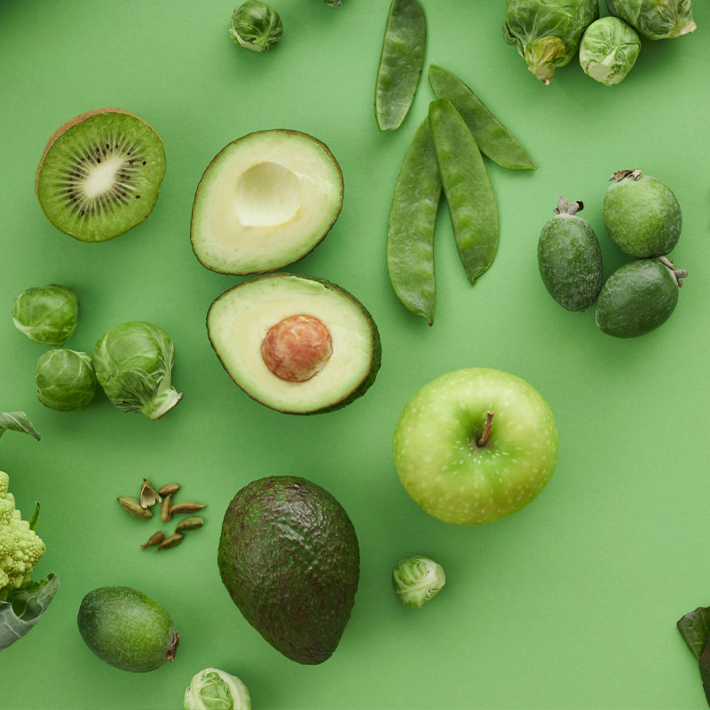 Een kleurrijke verzameling fruit en groenten op een groene achtergrond.