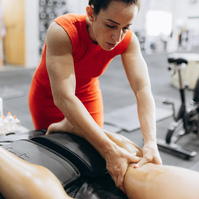 De handen van een fysiotherapeut masseren een overbelaste knie