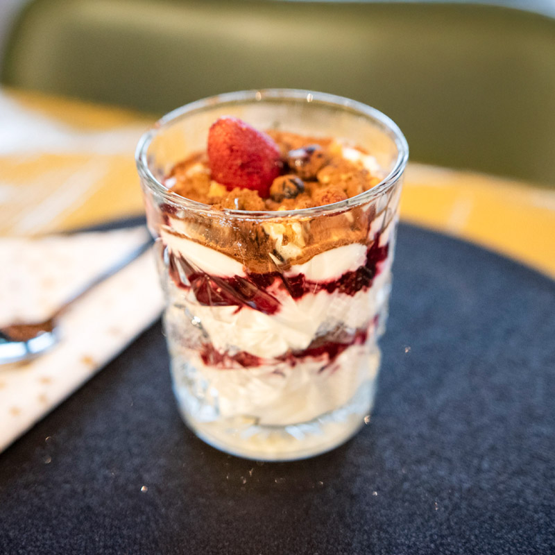 Glazen beker met een verfrissend dessert van kwark, frambozenmoes, blauwe bessen en aardbeien